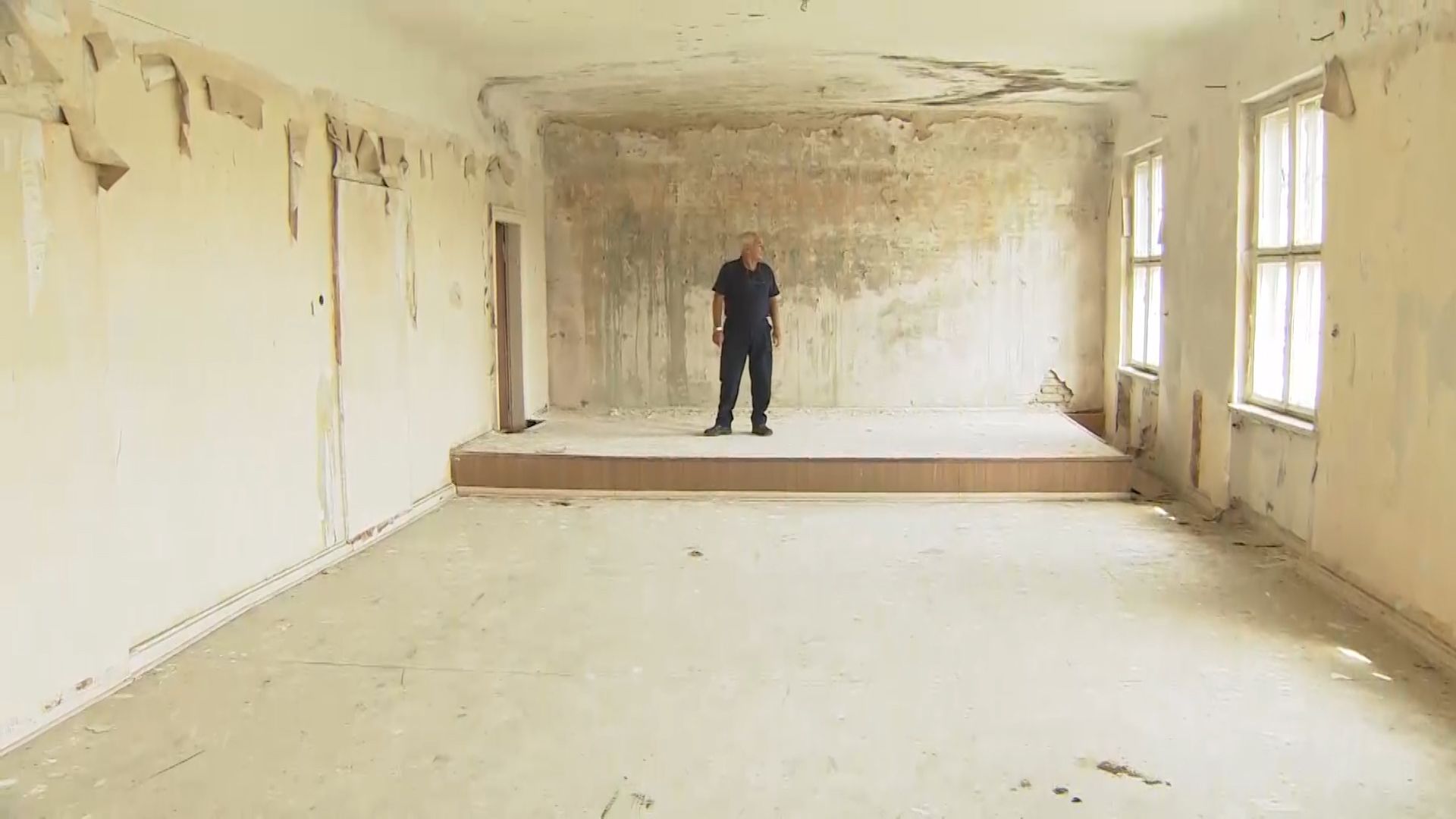 Dave Butler standing in an empty room with a "stage" at the Secret Village.